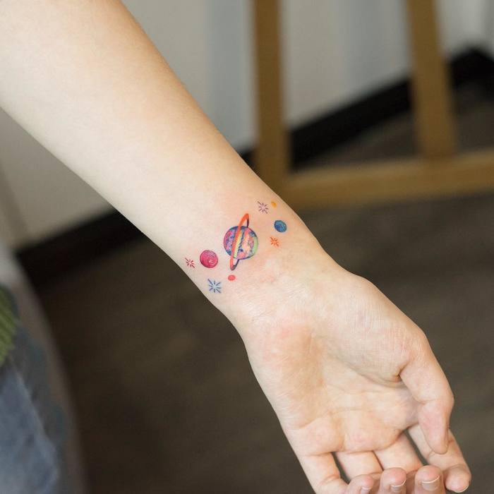 Colorful Tiny Planets on wrist by zihee_tattoo